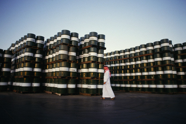 December 1986, Jiddah, Saudi Arabia --- Man wearing traditional suit and kaffiyeh in front of oil barrels at Jeddah Oil Refinery. --- Image by © Dominique Aubert/Sygma/Corbis